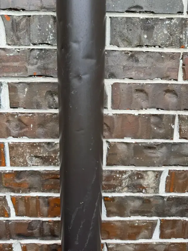 Brown rain gutter against a brick wall.